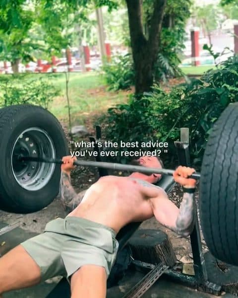 Rob bench-pressing a bar loaded with tyres, outdoors